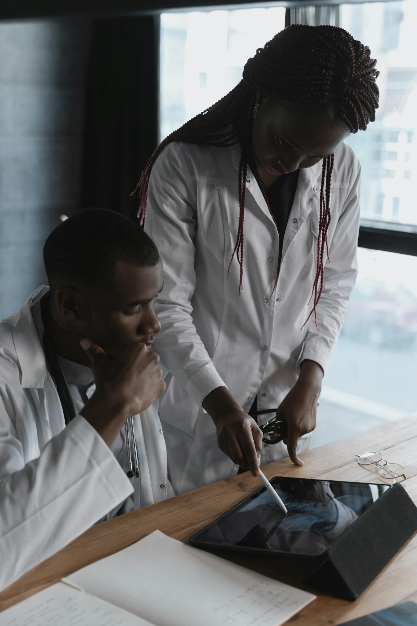 Two doctors in lab coats focus on research in a modern office setting, collaborating effectively.
